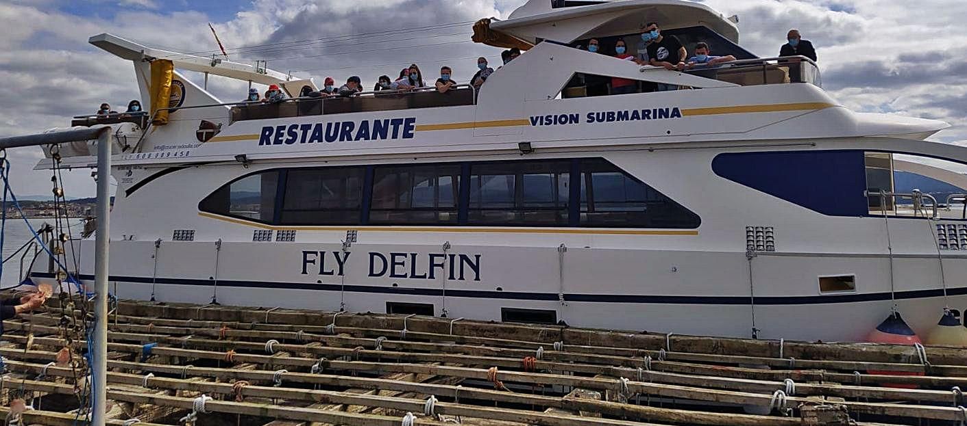 El “Fly Delfín”, abarloado a una batea para mostrar el cultivo de mejillón.