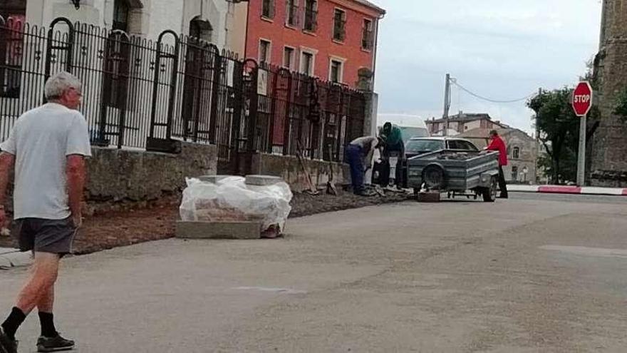 Un vecino y operarios trabajando en una calle de Alcañices.