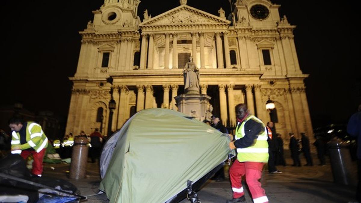 Un agente desmonta una de las tiendas de los indignados, frente a la catedral de Saint Paul, en el centro de Londres.