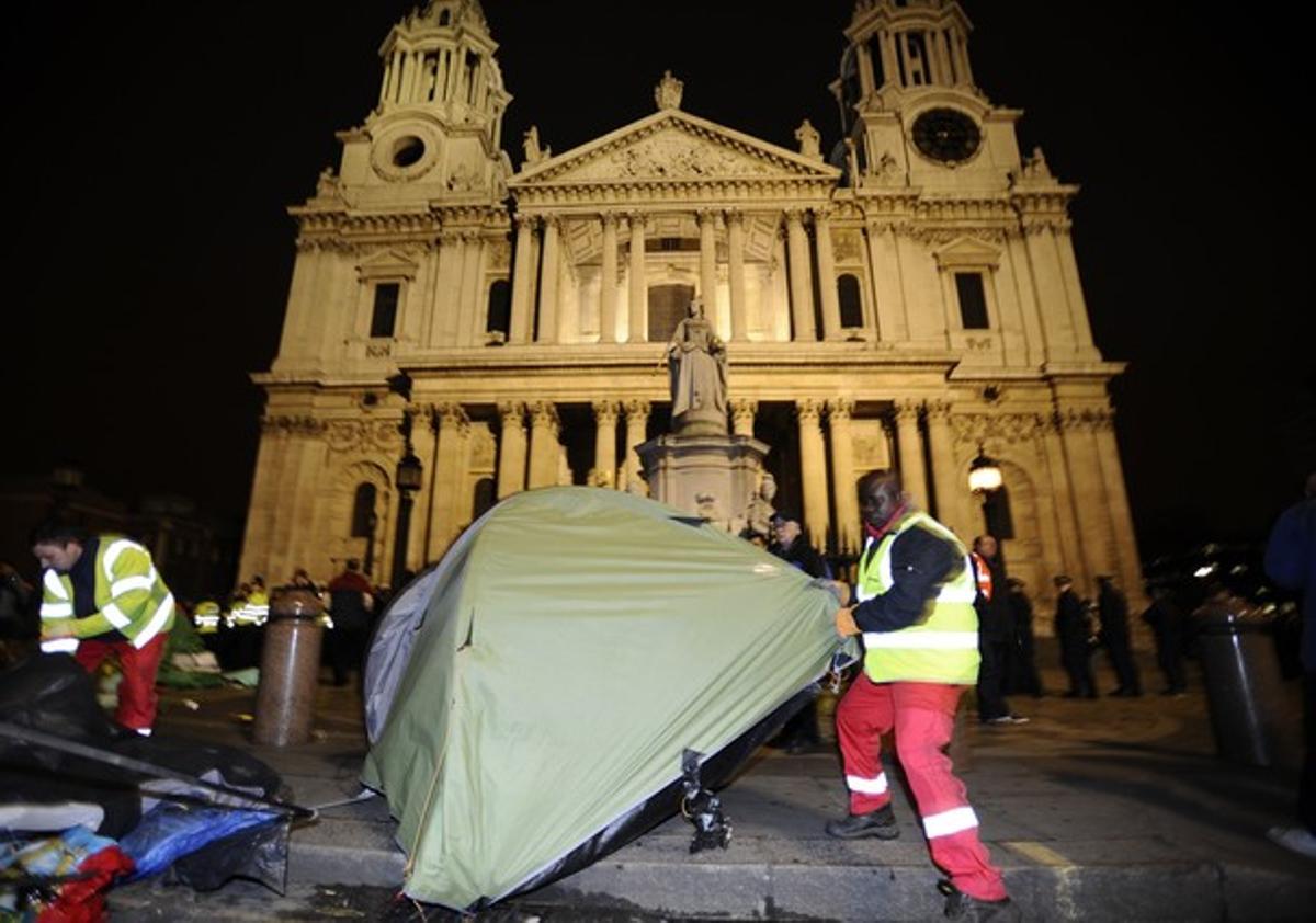 Un agent desmunta una de les tendes dels indignats, davant la catedral de Sant Pau, al centre de Londres.