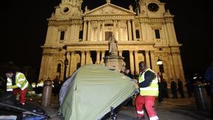 Un agent desmunta una de les tendes dels indignats, davant la catedral de Sant Pau, al centre de Londres.