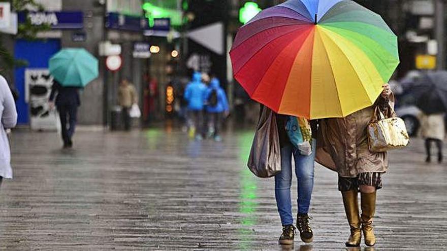 Dos personas se protegen de la lluvia en una calle de A Coruña.