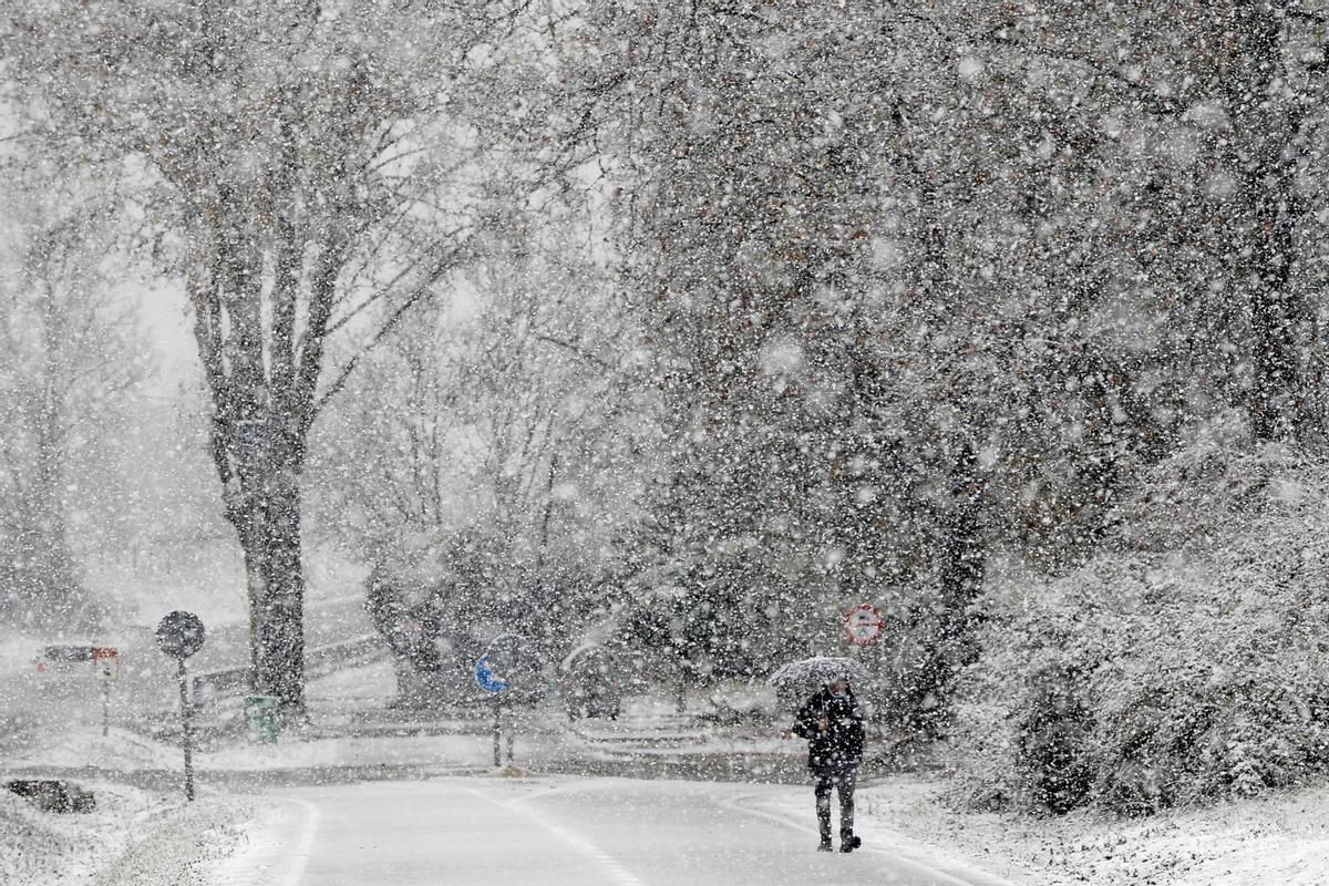 Un hombre pasea bajo la nieve caída esta mañana en Valladolid debido al temporal que afecta a la Península.