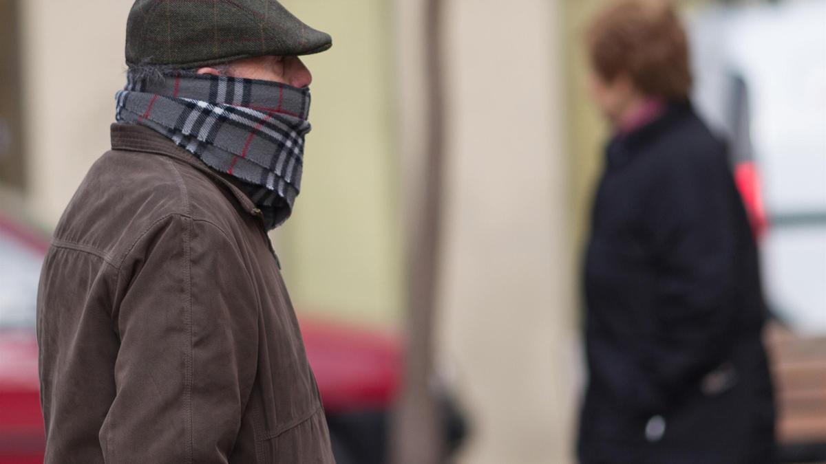 Un hombre, abrigado, se protege del frío.