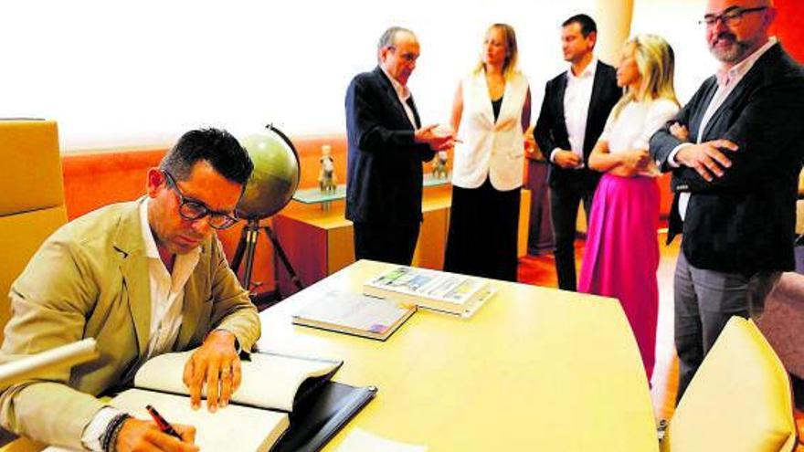 Rafael Triguero firma en el libro de honor junto a Javier Moll y los demás alcaldes.  | TONI ESCOBAR