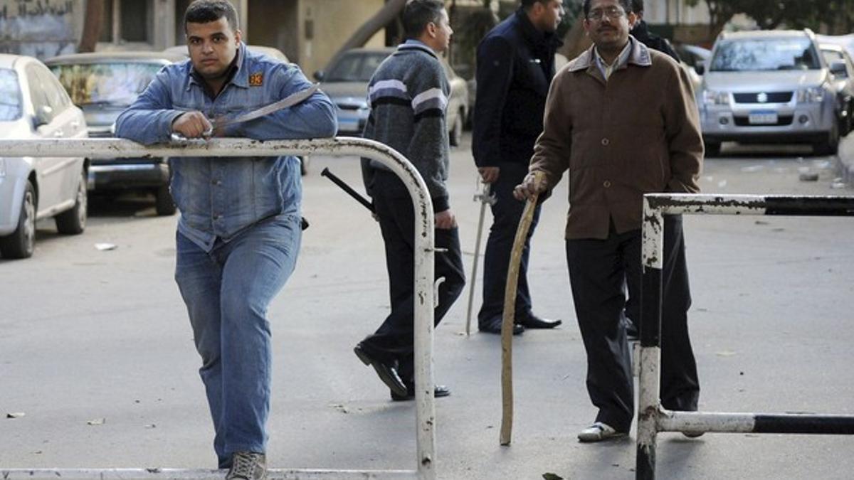 Un grupo de vecinos armados hace guardia a las puertas de sus hogares en El Cairo, el domingo.