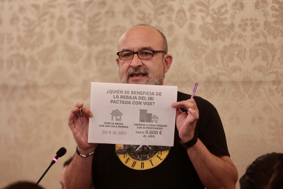 Manolo Copé, from Eu-Podos, shows a poster on the reduction of the IBI agreed by the PP and Vox.