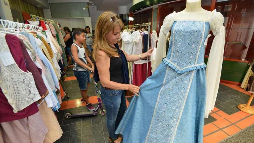 Una clienta observa un vestido en una de las tiendas de alquiler que ya ha abierto sus puertas. // G.S.