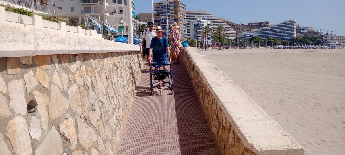 Algunos vecinos descienden por la rampa de acceso a la playa de Cullera.