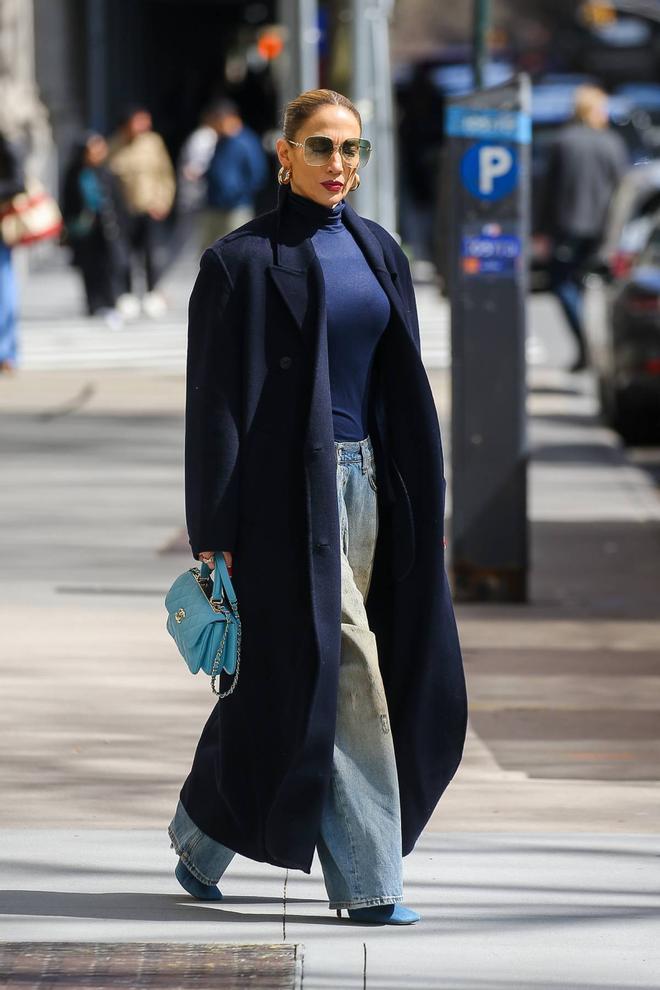 Jennifer Lopez con vaqueros, abrigo azul marino y minibolso