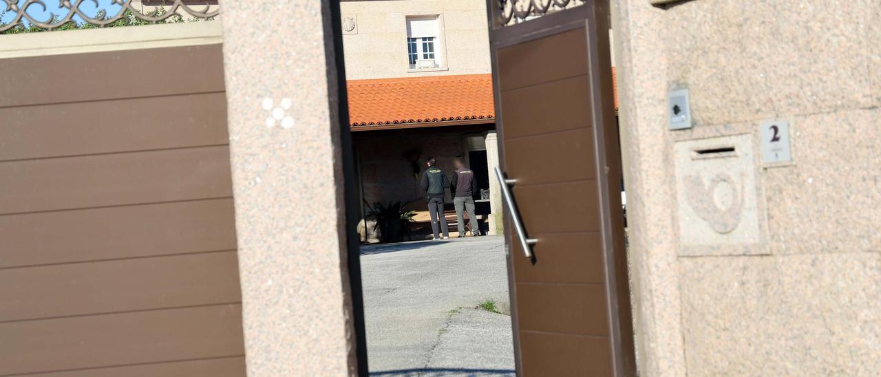 Dos agentes en la entrada de la vivienda, desde el exterior de la parcela.