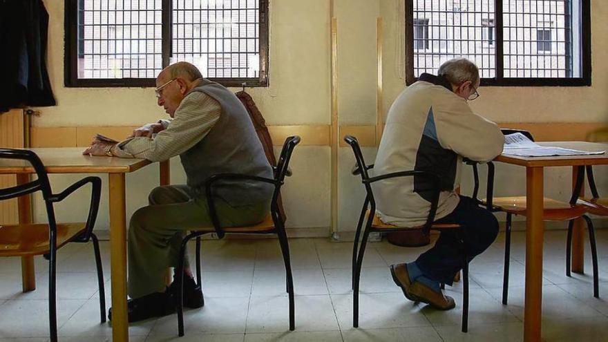 Dos jubilados leen el periódico en un local social para la tercera edad.