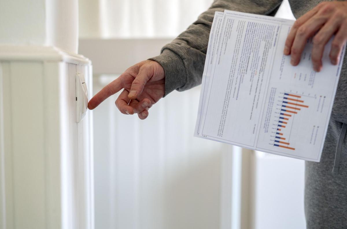 Archivo - Un hombre enciende un interruptor con una factura de luz en la mano, a 3 de enero de 2022, en Madrid, (España).