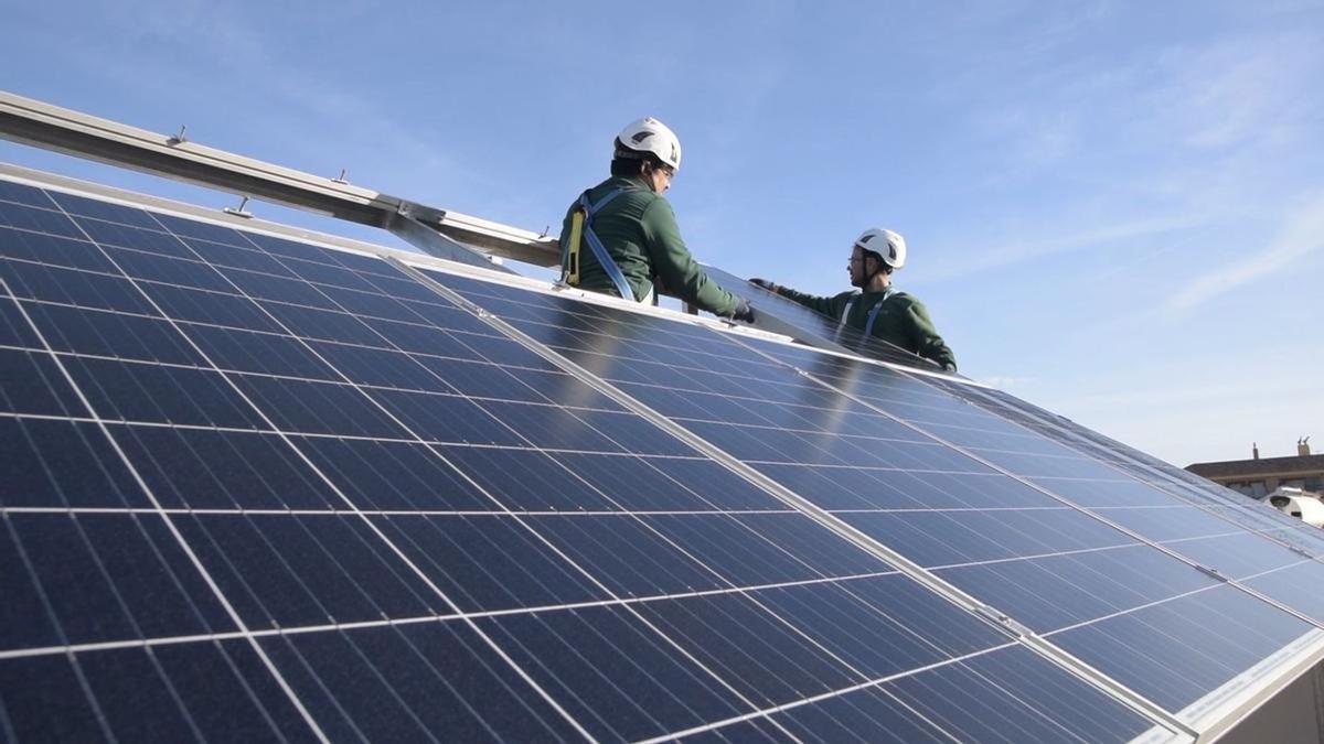 Dos operarios instalan paneles solares para el autoconsumo.