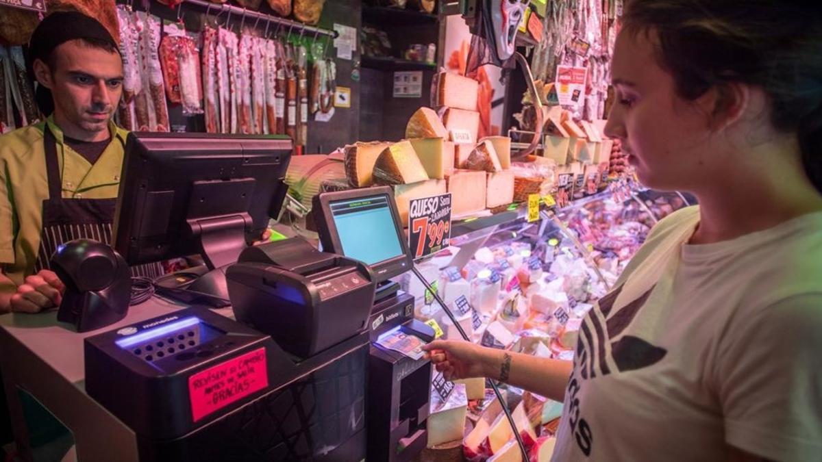 Una clienta paga en una de las tiendas Germans Gracia de Barcelona en una máquina que devuelve el cambio.