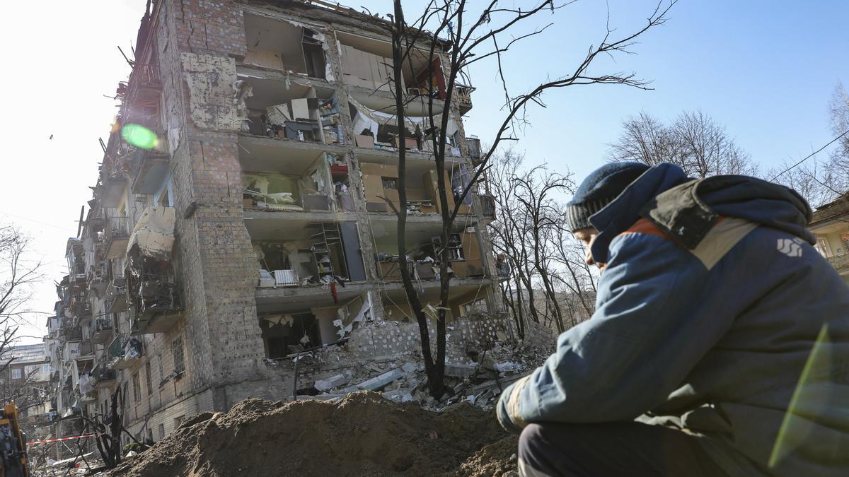 Un hombre sentado frente a un edificio bombardeado en el área de Kiev.