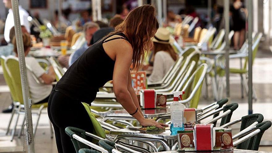 Una camarera limpia una mesa en la terraza de un bar de València.