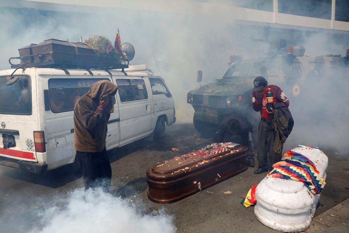 Supporters of former Bolivian President Evo Morales take cover from tear gas while carrying coffins of people they say were killed during recent clashes with security forces in Senkata, as they take part in a protest, in La Paz, Bolivia November 21, 2019. REUTERS/Marco Bello     TPX IMAGES OF THE DAY