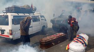 Supporters of former Bolivian President Evo Morales take cover from tear gas while carrying coffins of people they say were killed during recent clashes with security forces in Senkata, as they take part in a protest, in La Paz, Bolivia November 21, 2019. REUTERS/Marco Bello     TPX IMAGES OF THE DAY