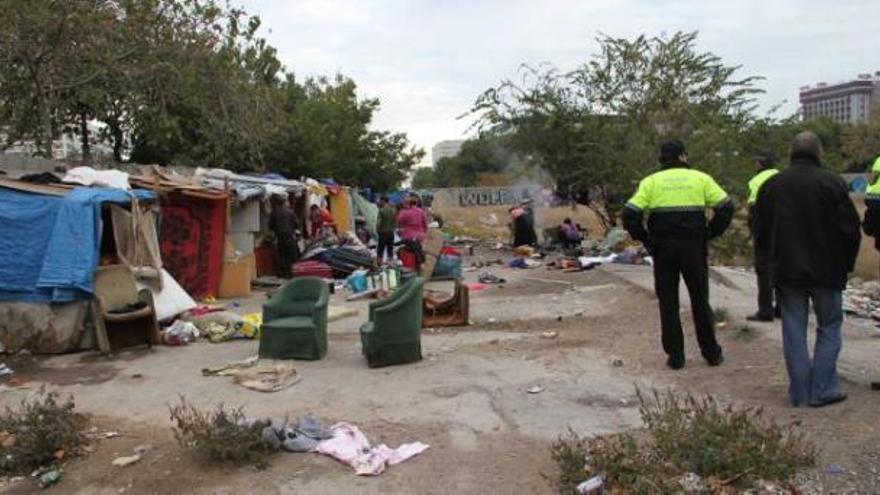 Agentes de la Policía Local observan cómo los inmigrantes recogen sus enseres personales.