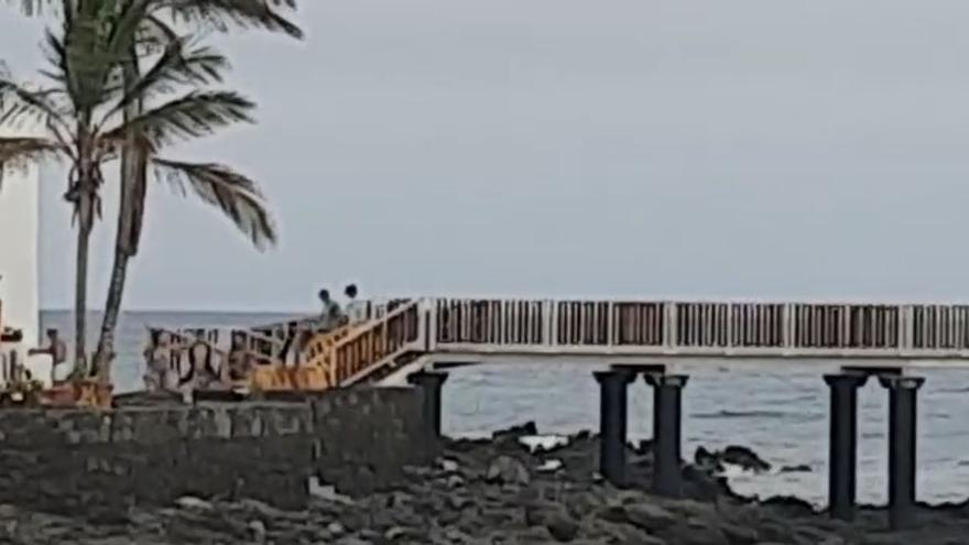 Jóvenes saltando las vallas de la pasarela para acceder al paseo de La Garita, Arrieta.