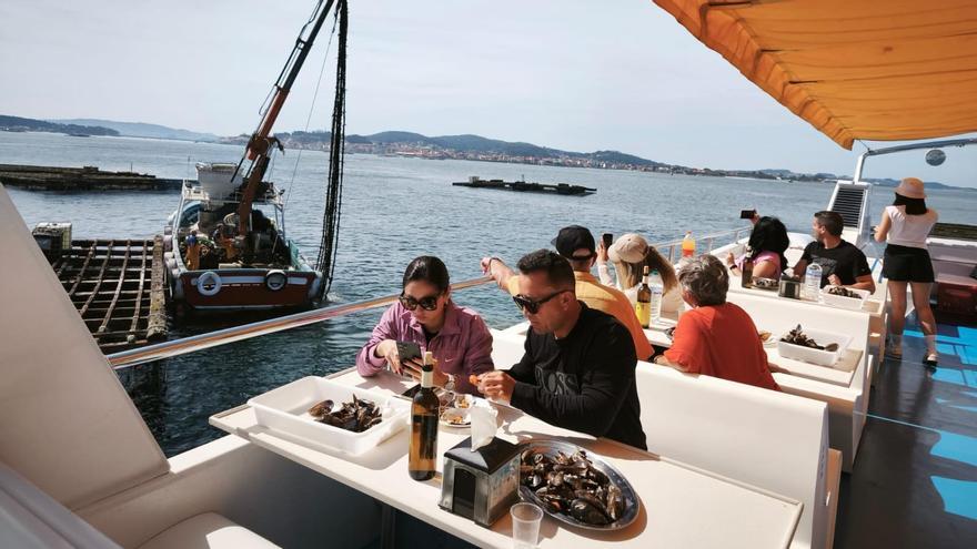 Turistas saboreando mejillones y ostras a bordo de un catamarán mientras observan el trabajo de los bateeiros, ayer.
