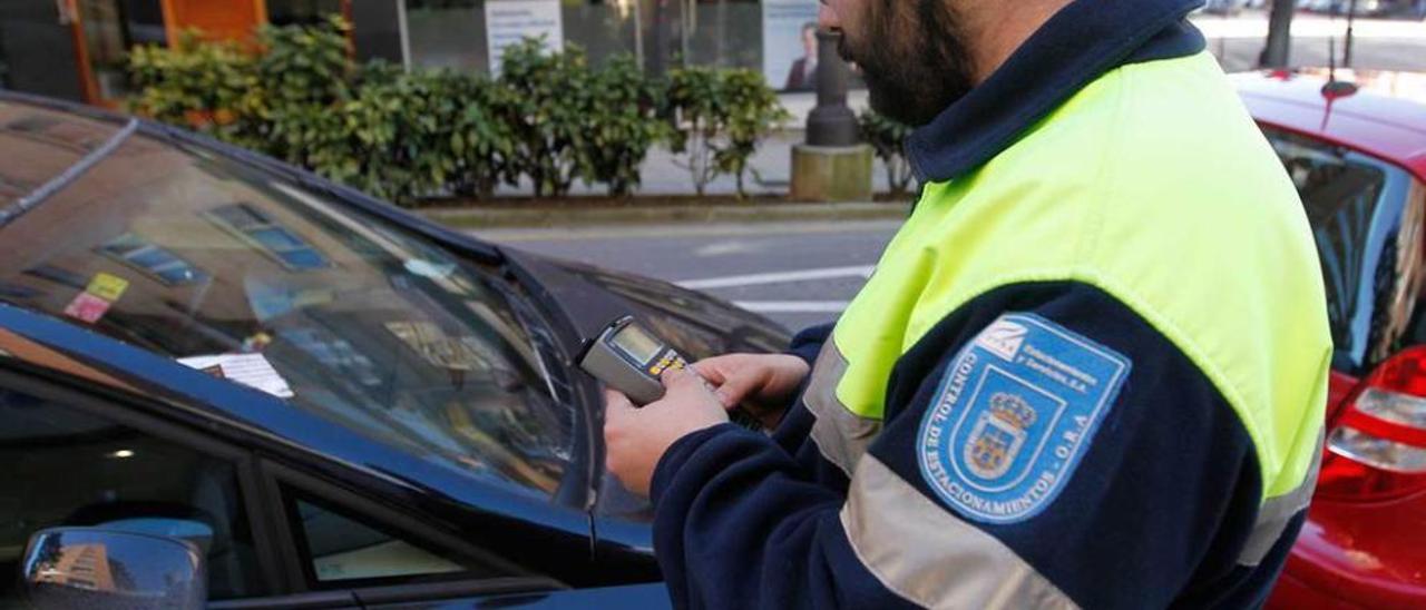 Un vigilante multa a un vehículo estacionado en la zona azul.