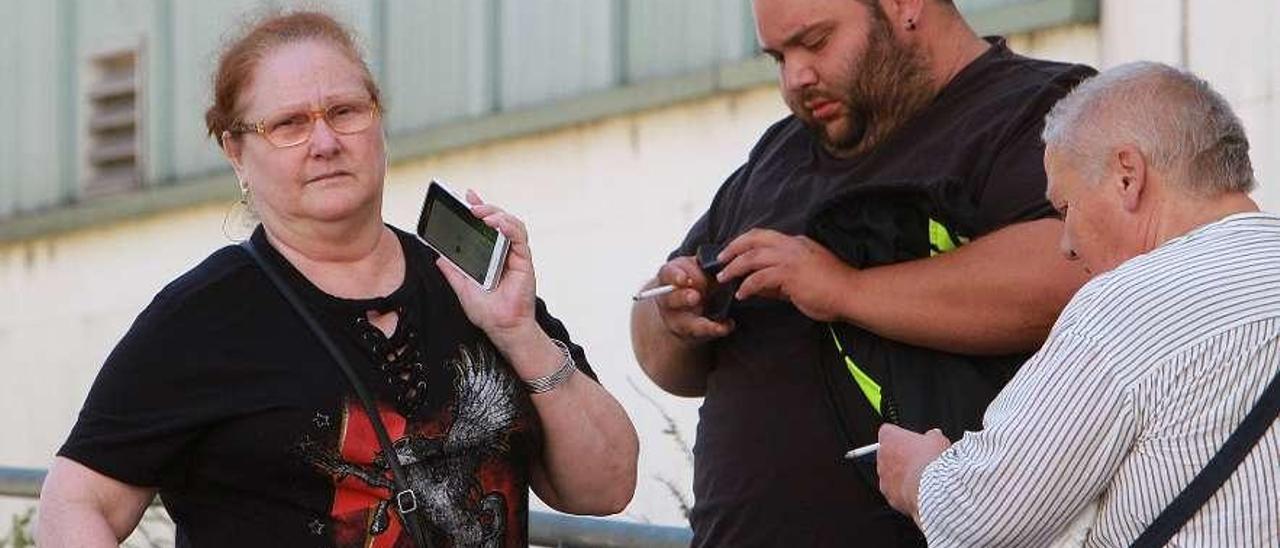 Una mujer atiende una llamada, mientras dos personas usan el móvil, en Ourense. // Iñaki Osorio