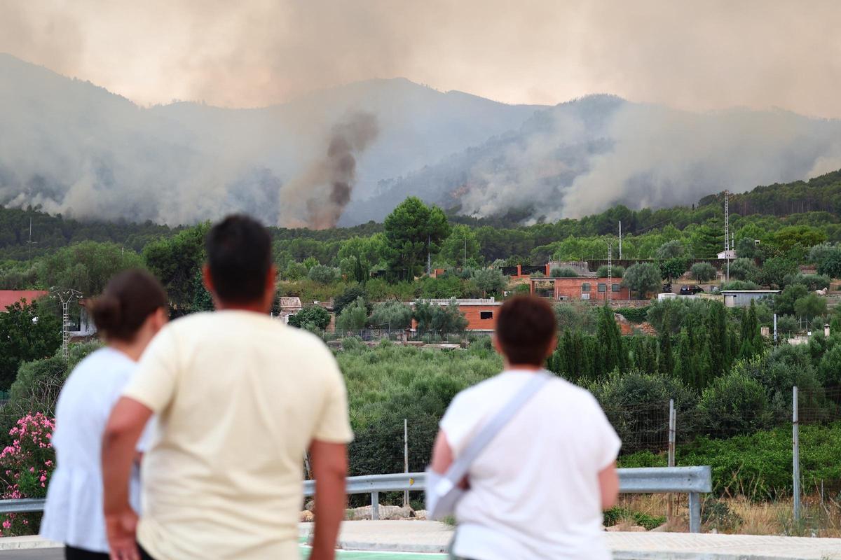 Unos vecinos siguen la evolución de las llamas en el término municipal de la Vall d'Uixó, este domingo.