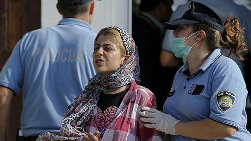 Una policía croata conduce a una mujer llegada de Serbia.