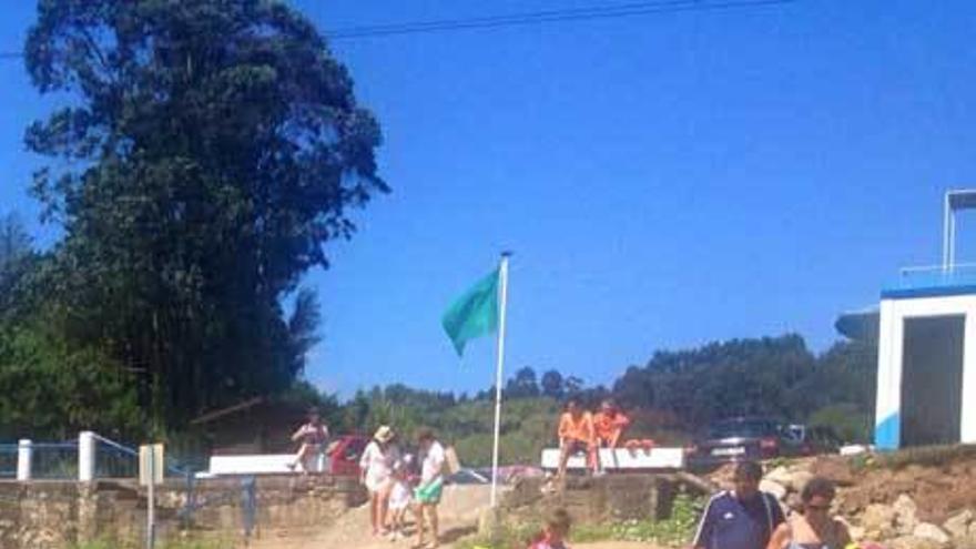 Usuarios tratando de acceder a la playa de El Astilleru, llena de piedras.