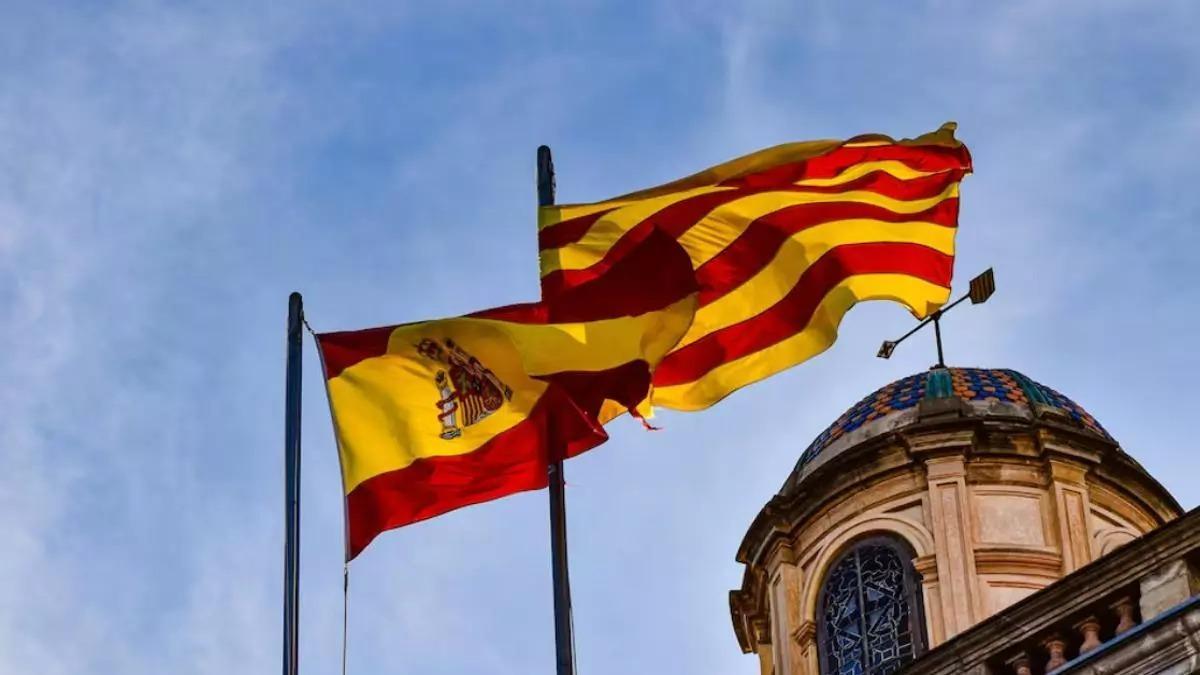 Una bandera española y una senyera ondean al viento. Una bandera española y una senyera ondean al viento.