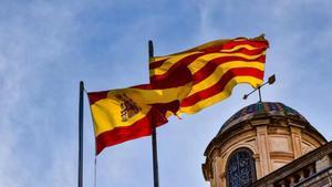 Una bandera española y una senyera ondean al viento.
