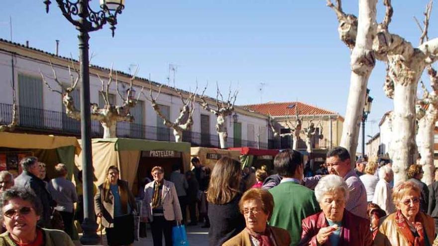 Ambiente en la Plaza Mayor de Fuentesaúco durante la tornaferia; a la derecha varias personas observan la exposición de fotografías de la Coral Saucana.
