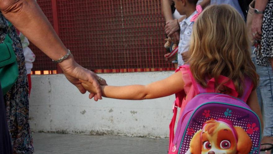 Una nena petita amb la motxilla penjada a l&#039;esquena, agafant la mà de la seva àvia.