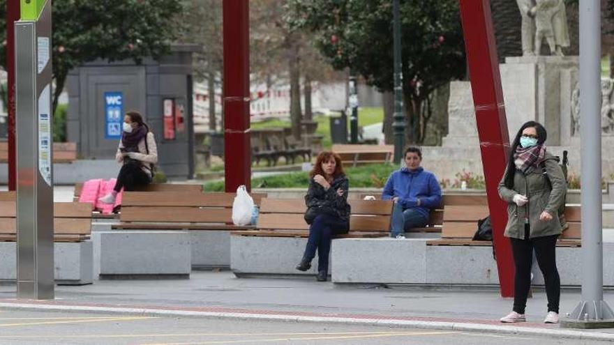 Varias personas esperan en la parada de bus de Plaza América. // R. Grobas