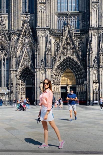 Hiba Abouk posa frente a la catedral de Colonia con una minifalda vaquera, deportivas rosas y camisa anudada a juego