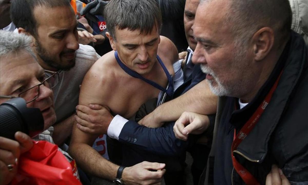 El vicepresidente de recursos humanos de Air France, Xavier Broseta, sin camisa, es evacuado por los agentes de seguridad después de que empleados de la compañía irrumpieran en la reunión que se estaba celebrando en el cuartel general de Air France, en el aeropuerto Charles de Gaulle de París.