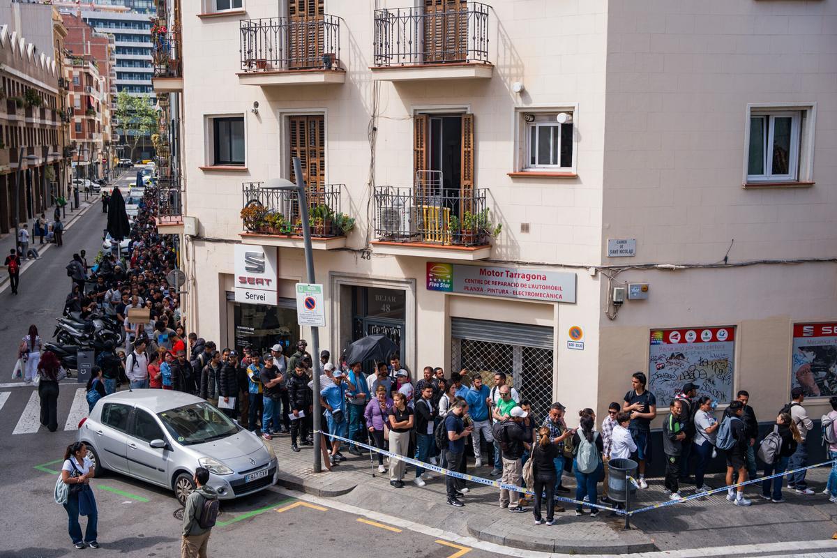 Caos y una larga cola de personas que esperan regularizar su situación en España en la Oficina de Benestar Social i Família de Barcelona-Sants/Eixample.