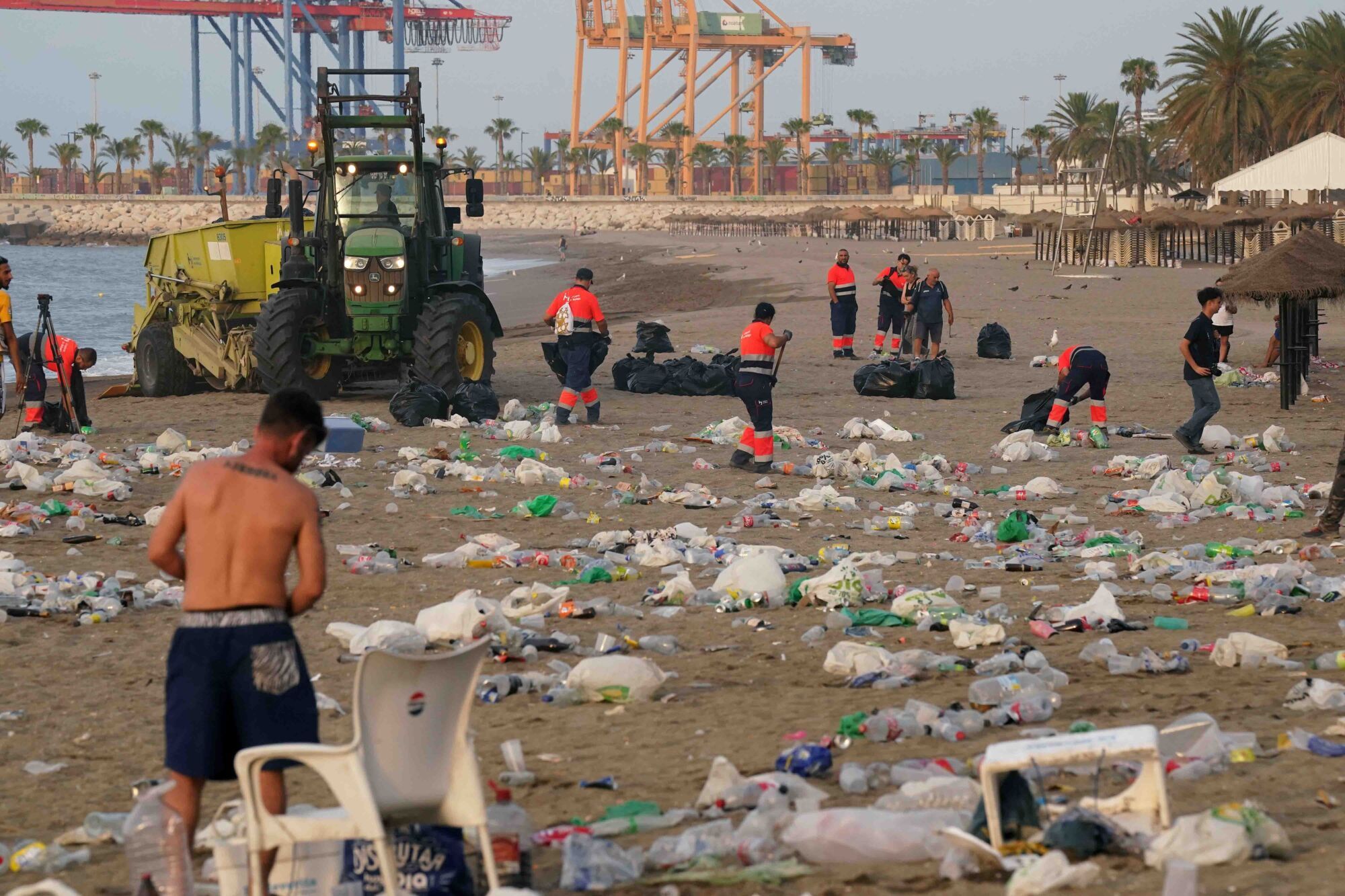 Varios operarios de la empresa de limpieza de Limasam, recogen los residuos de la playa de La Malagueta, tras la Noche de San Juan en Málaga 2025