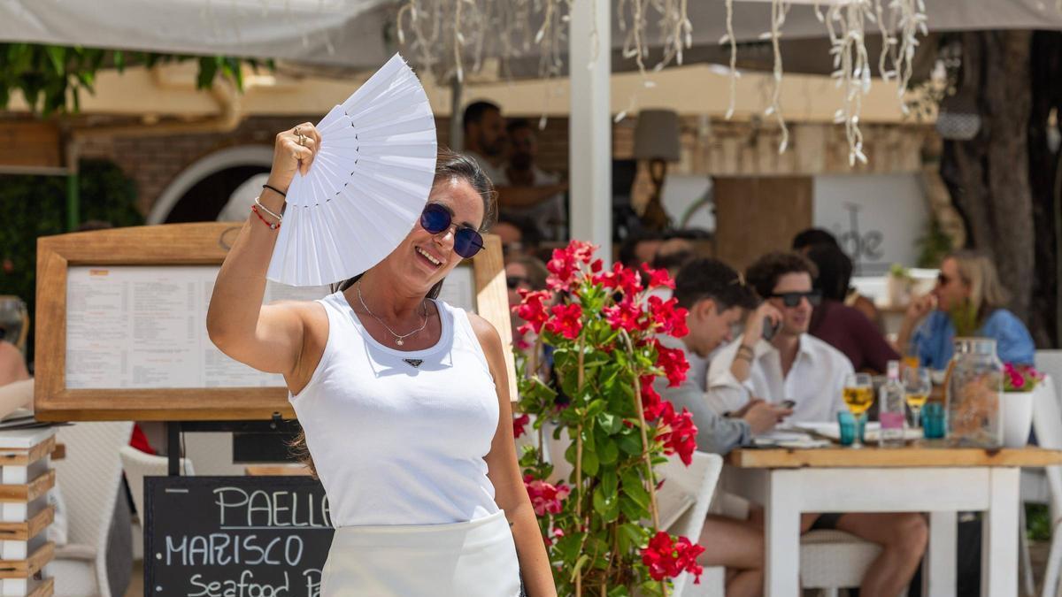 Una turista utiliza su abanico contra el viento en ses Figueretes.