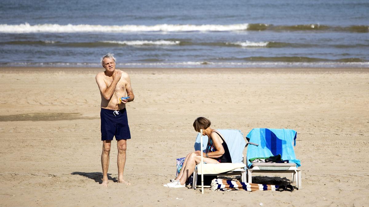Un hombre se unta con crema solar y una mujer se acomoda en su hamaca, en una playa en Zandvoort, Países Bajos, durante la intensa ola de calor que recorre Europa.