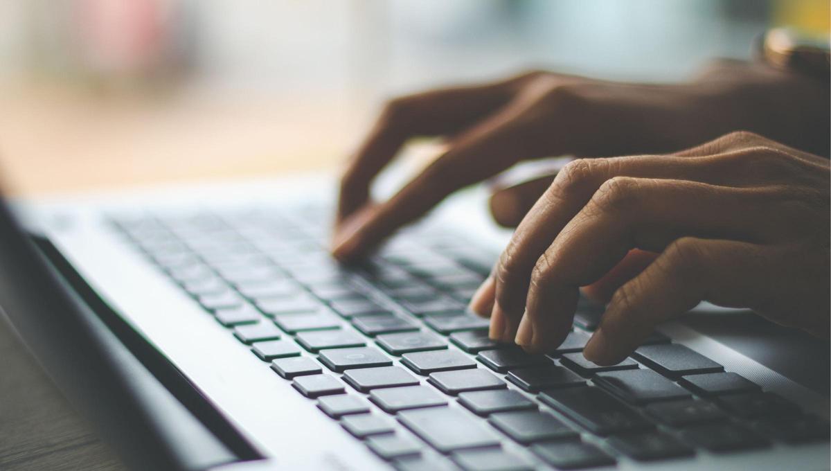 Una persona escribiendo en un ordenador.