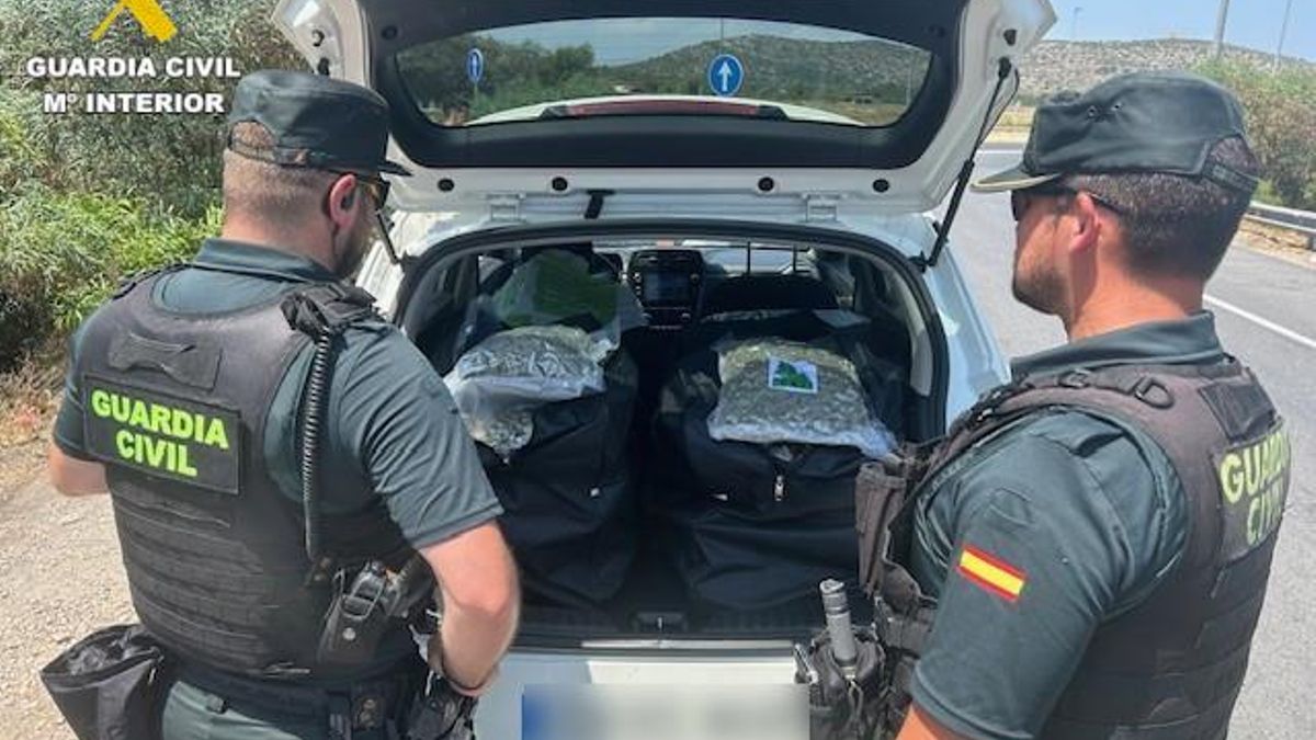 Los agentes, junto al vehículo que portaba la droga.