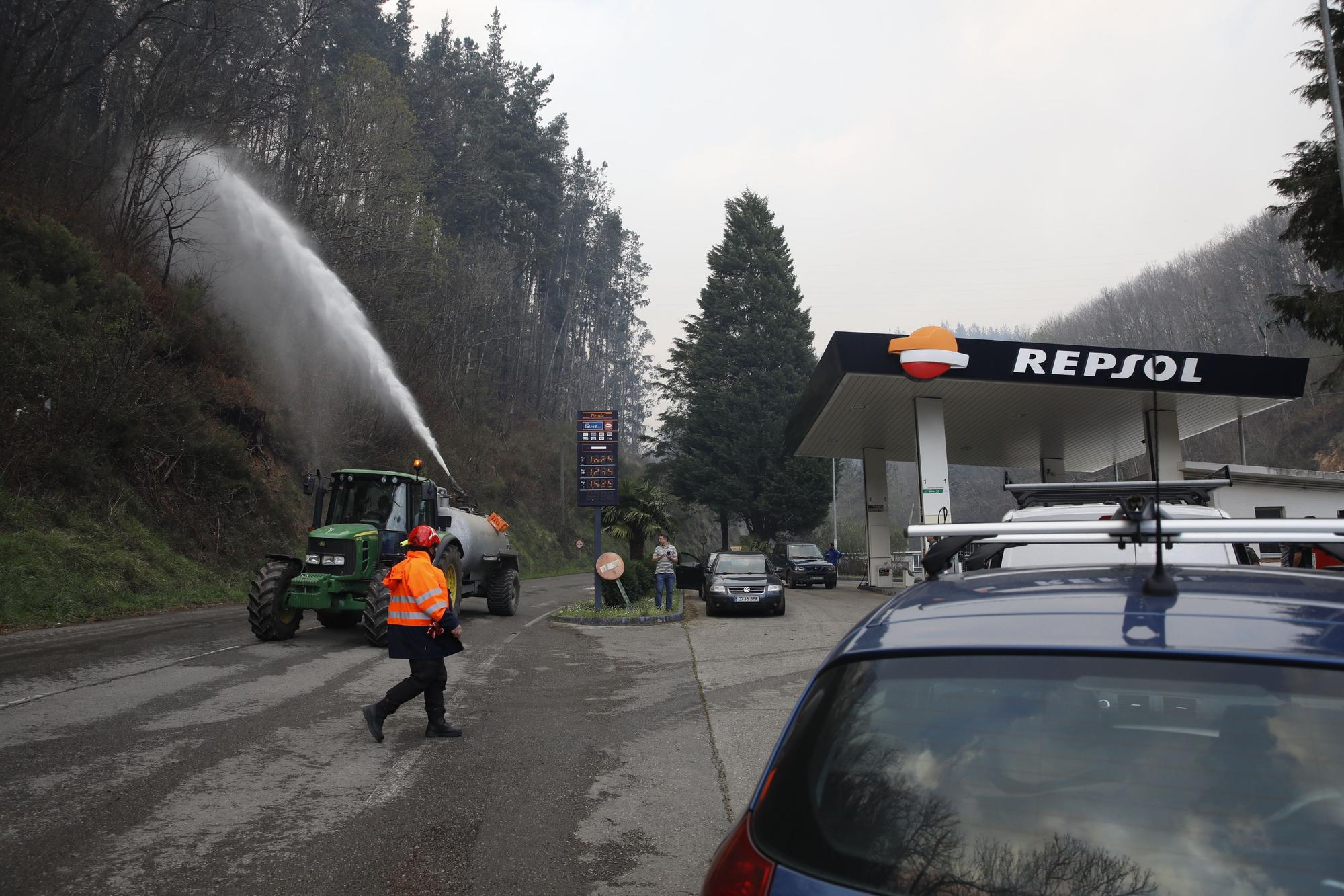 Agricultores ayudando en la extinción de los focos de fuego y enfriando las inmediaciones de la gasolinera de Navelgas