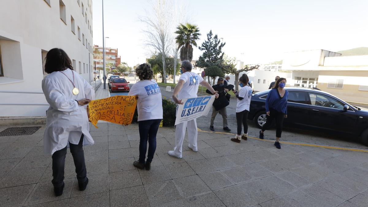 Un grupo de sanitarios reciben a Armengol de espaldas y con pancartas de protesta.
