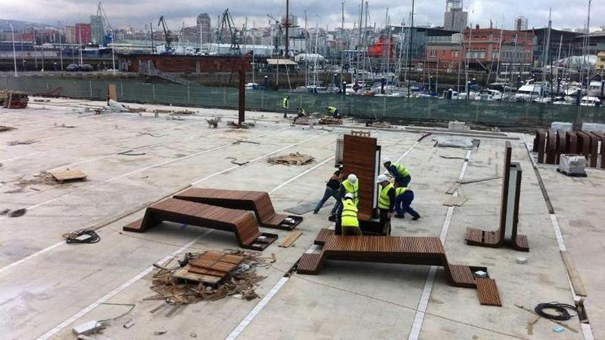 Un grupo de operarios trabaja con el mobiliario urbano que se instalará encima del &#039;parking&#039; de O Parrote. m. m.