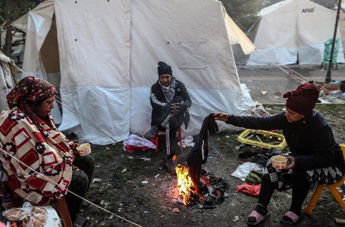 Personas desayunando entre tiendas de campaña en Hatay cinco días después del terremoto que ha devastado varias ciudades en Turquía