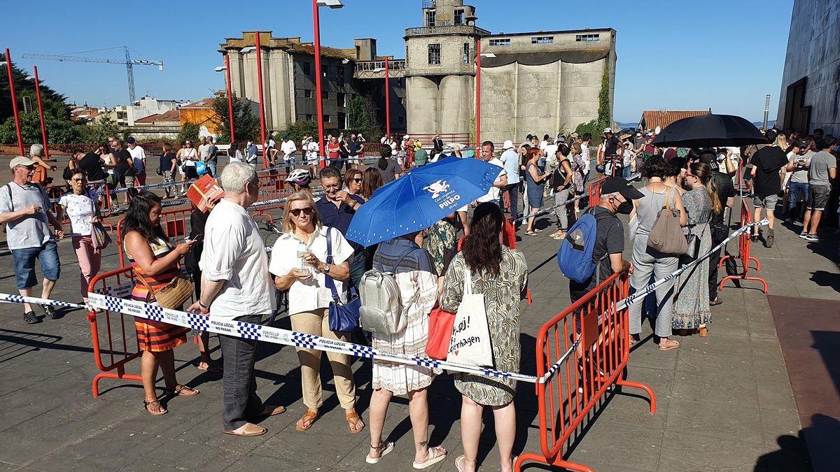 Gente protegiéndose del sol en la praza do Rei, esperando a comprar entradas para el concierto de Sting.