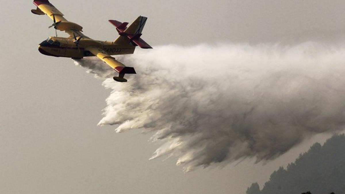 Un avión lanza agua para extinguir el fuego sobre Boadella, el martes.